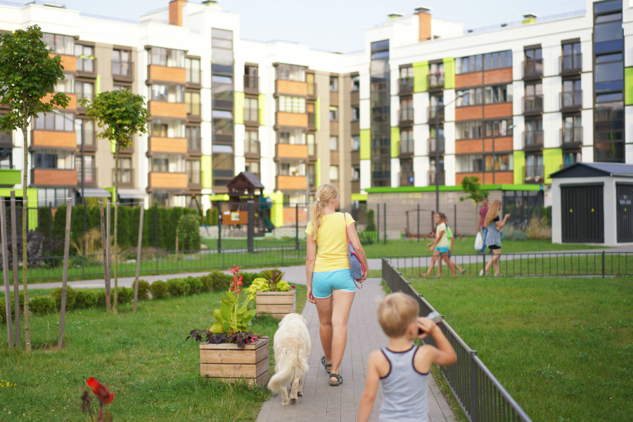 vrouw met kinderen loopt over pad naar een flatgebouw